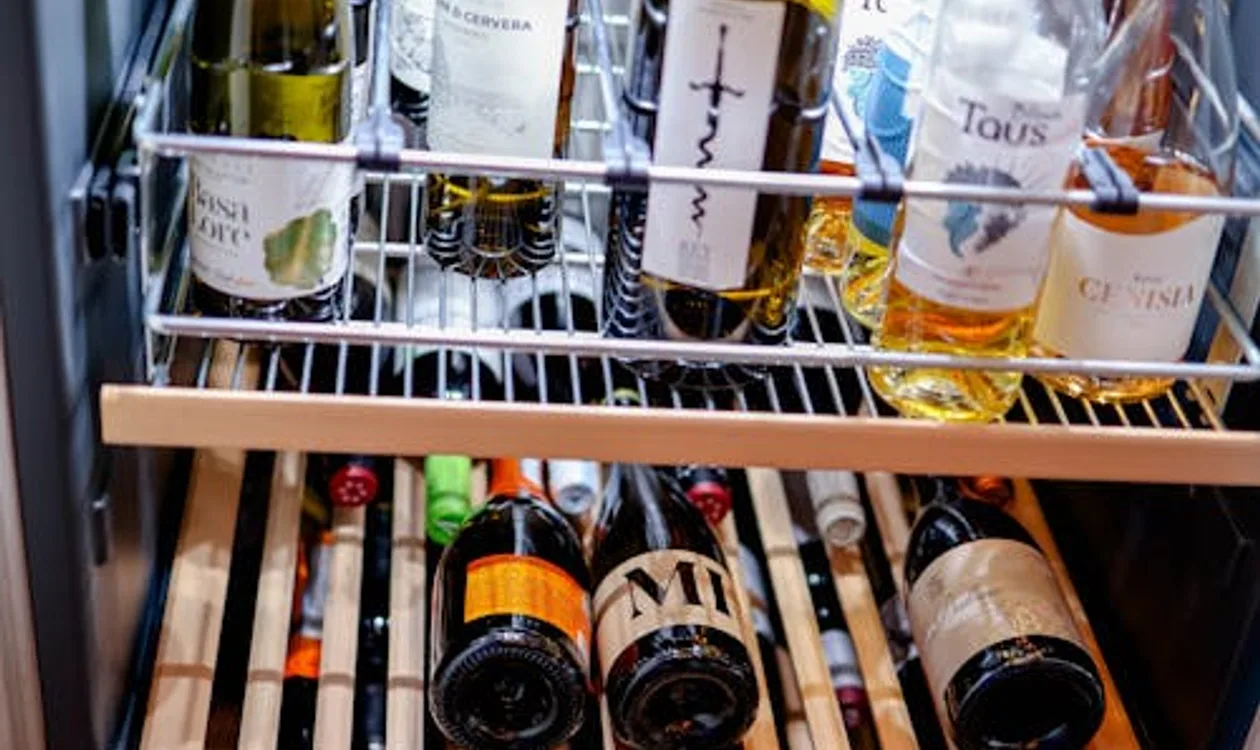 Wine bottles stored in a modern wine cooler with glass door
