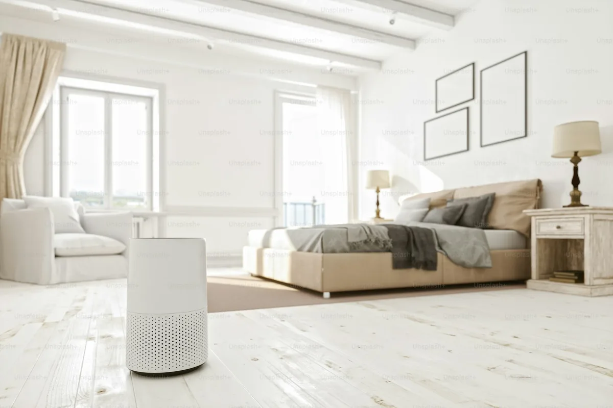 White tower air purifier running beside a sofa in a sunlit living room