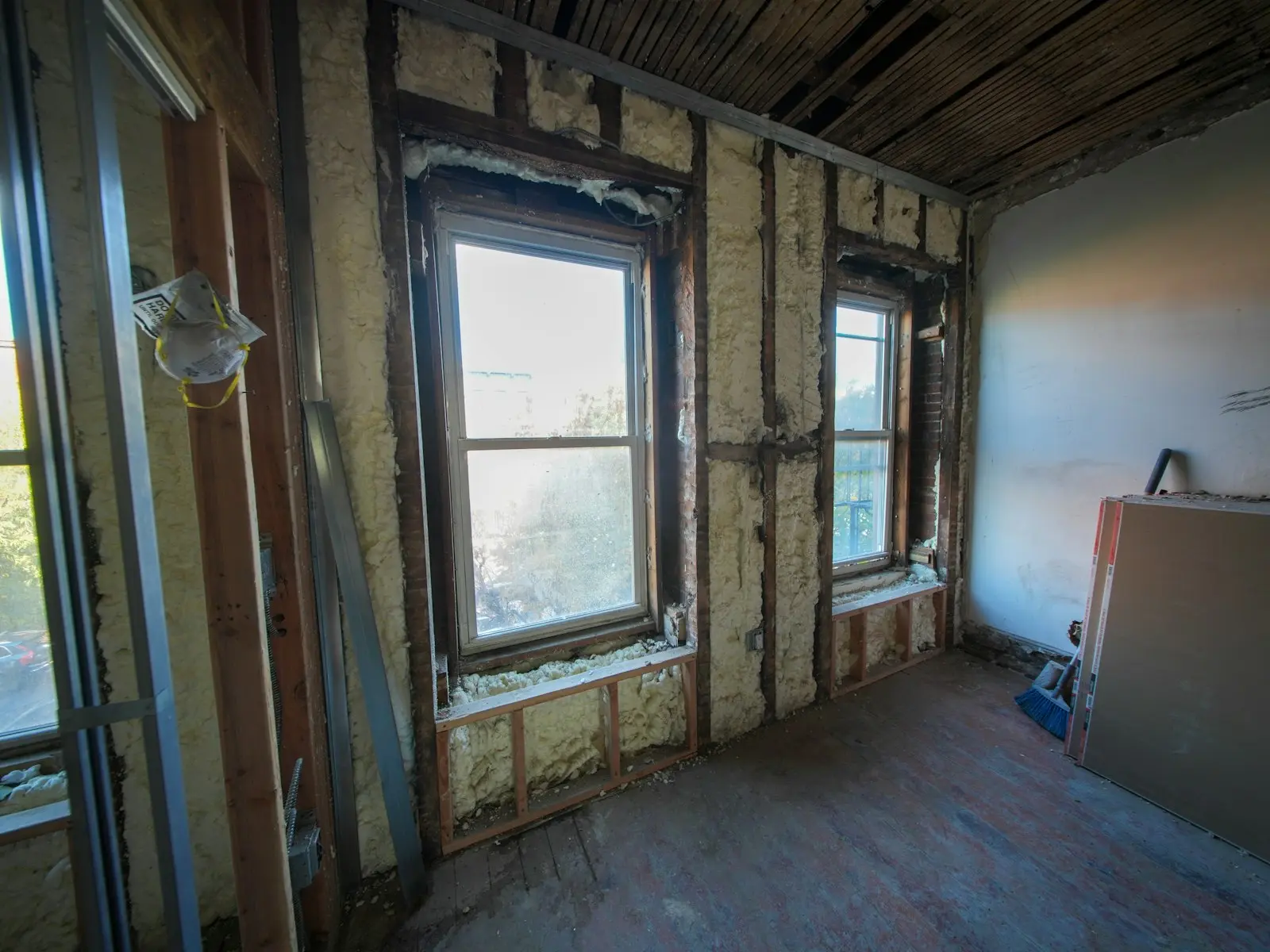A room under construction with exposed wall insulation and windows