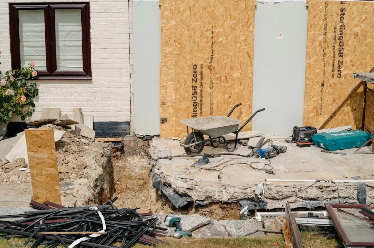 An older house mid-renovation with its foundation exposed and equipment outside