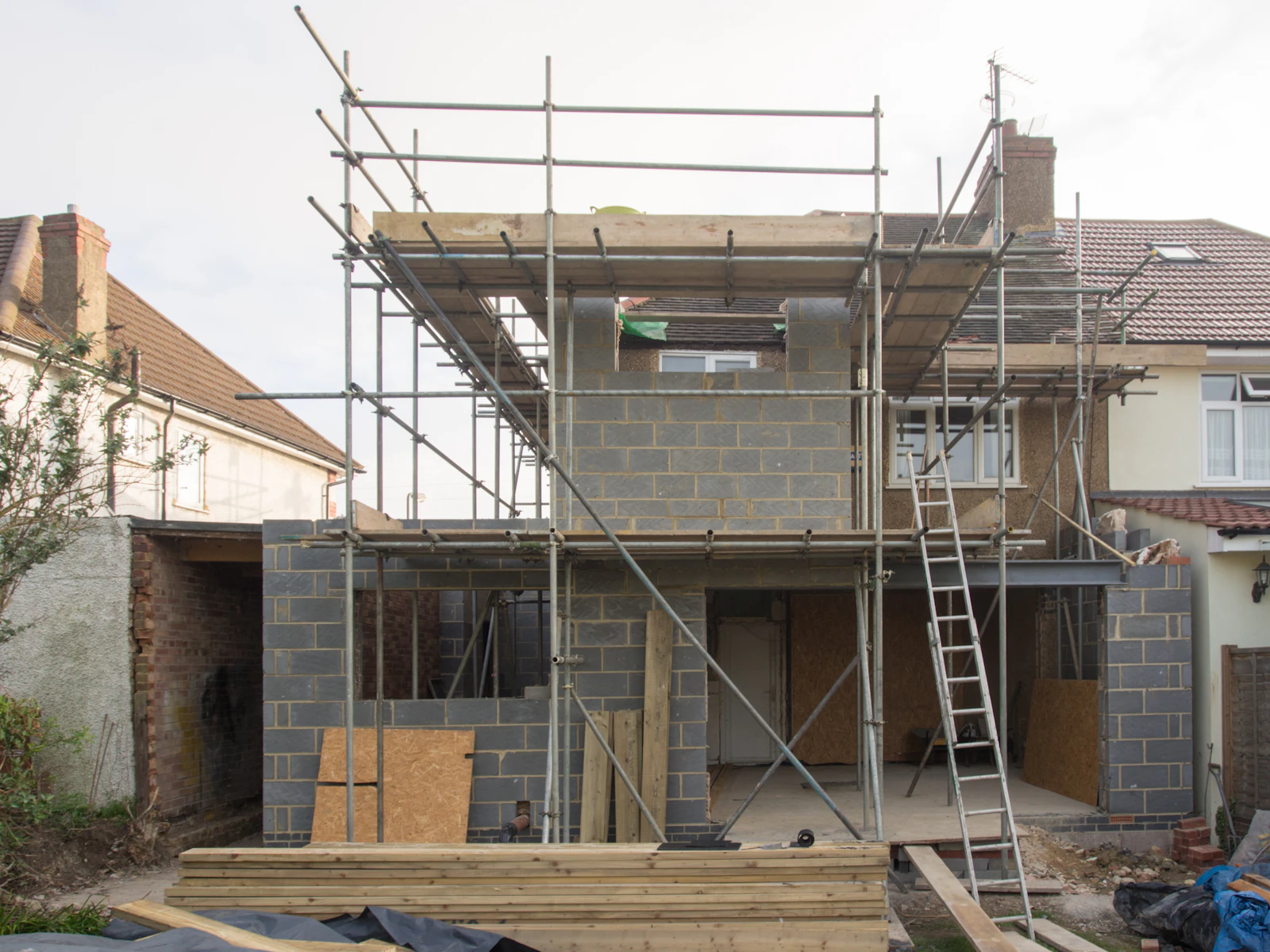 A brown brick house extension under construction on a bright day