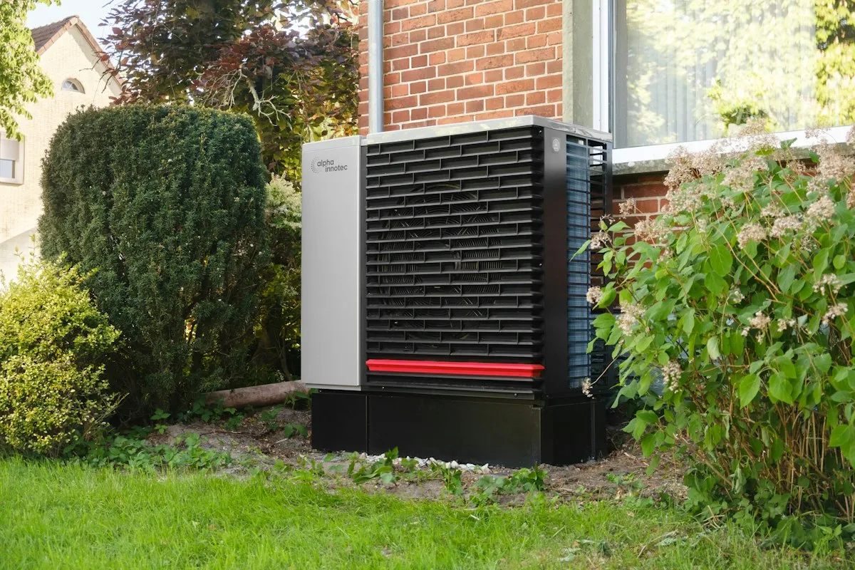 A modern heat pump outdoor unit installed beside a renovated brick house