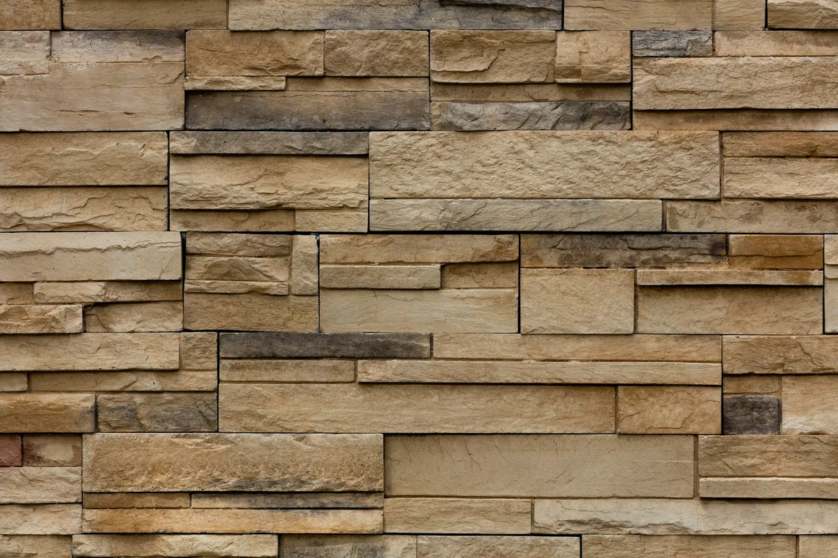 A weathered brown brick wall with worn mortar joints filling the frame