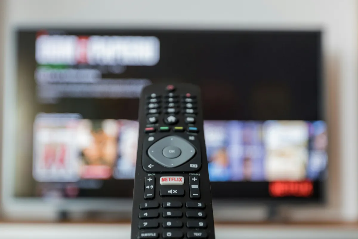 Black streaming remote resting on a brown wooden table
