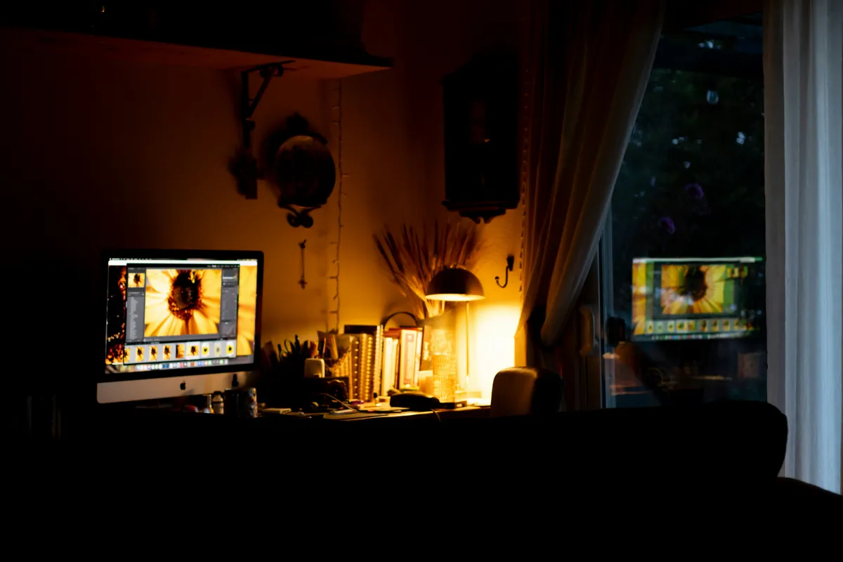 Dimly lit room with a glowing screen and a window reflection