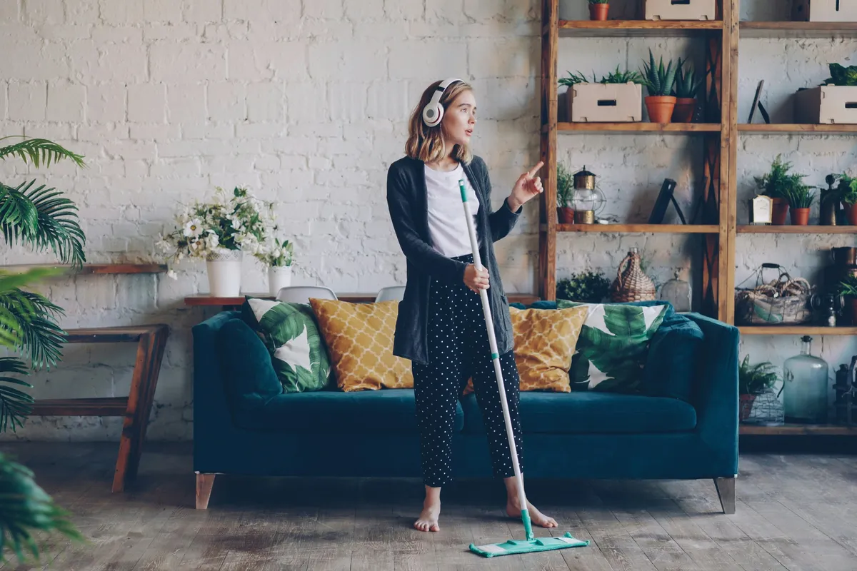 Person mopping a hard floor by hand in a bright room