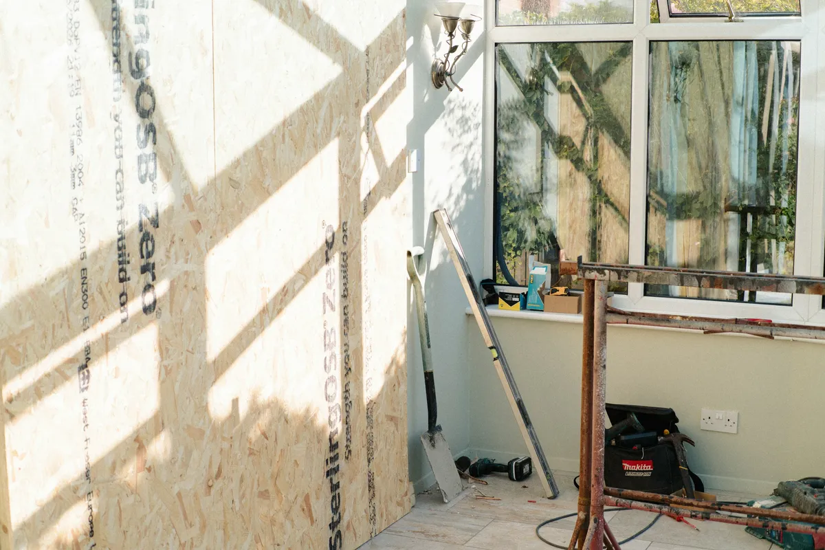 Bare OSB sheathing panels with printed stamps beside an open window in a part-built room