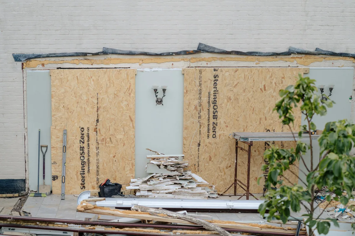 A wall stripped back during renovation, showing OSB sheathing panels alternating with rigid insulation board