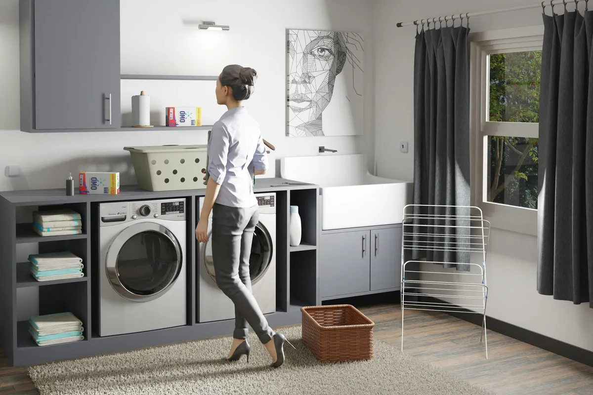 Person standing in a laundry room beside a washer and dryer