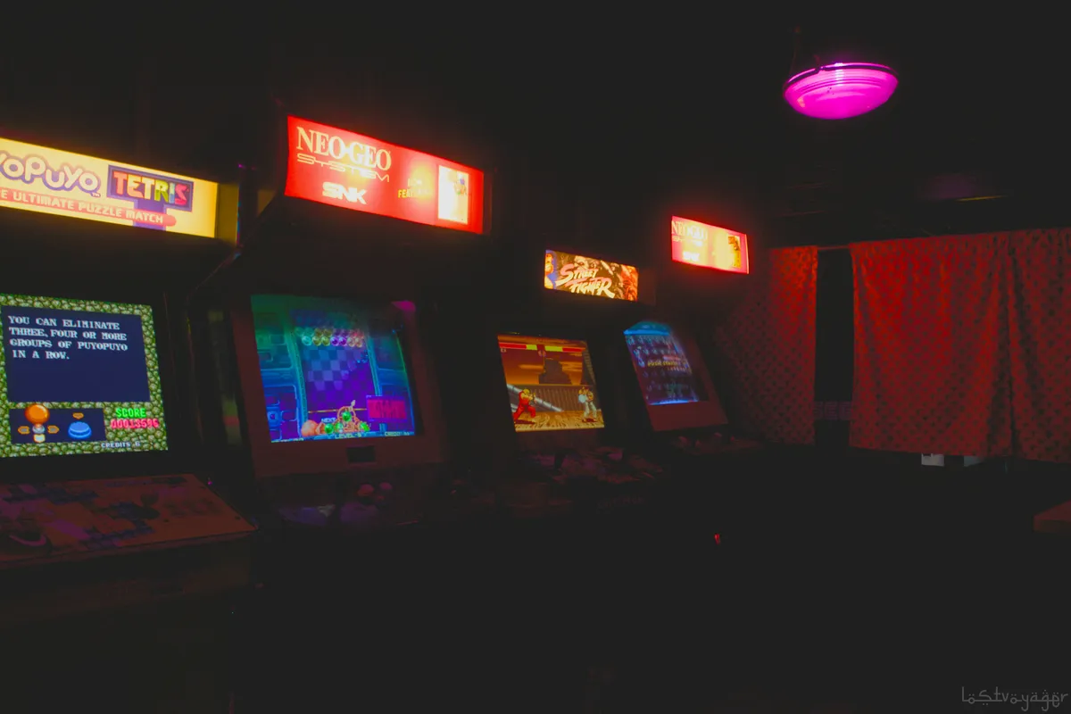Dark arcade room lit by rows of glowing game machine screens