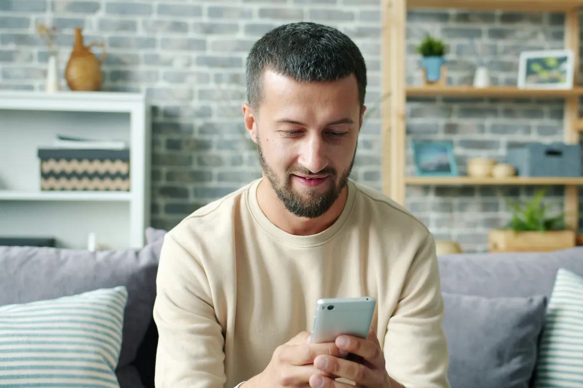 Person sitting on a couch tapping through an app on a phone