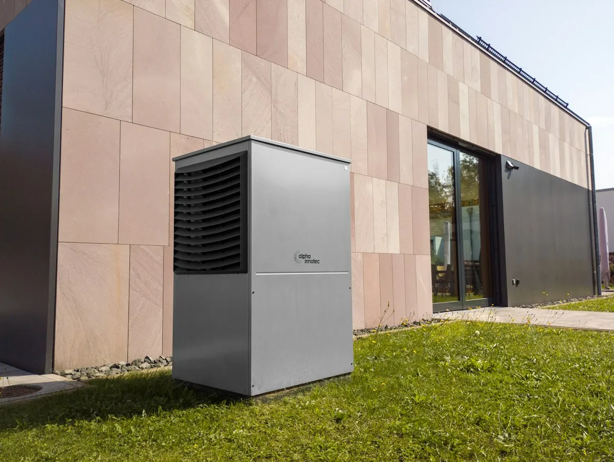 An outdoor heat pump unit on a lawn beside a modern home