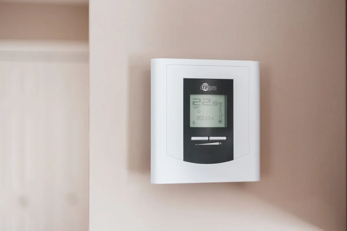 A wall thermostat showing the indoor temperature in a hallway