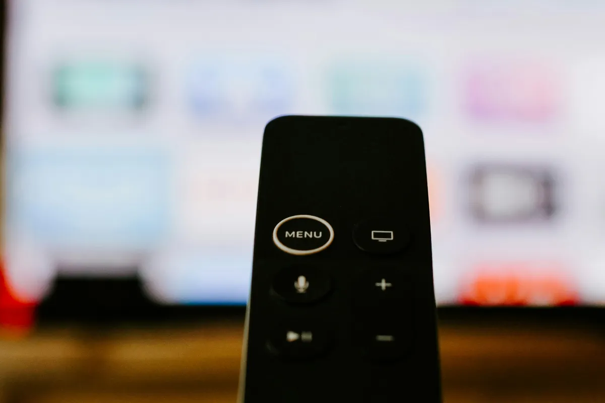 Slim black remote control photographed on a light surface