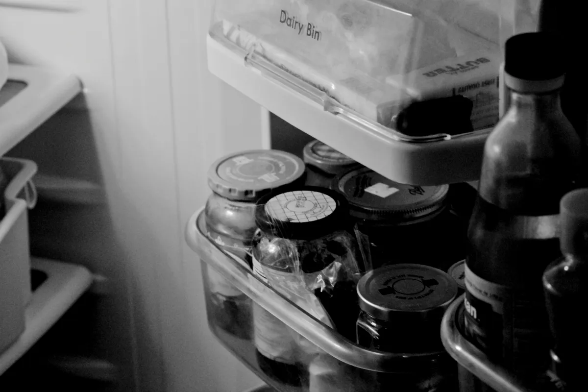 Glass storage jars lined up on white refrigerator shelves