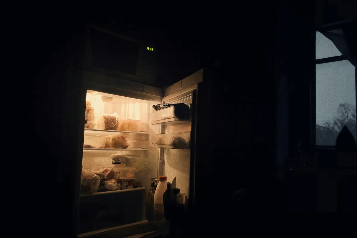 Open refrigerator standing in a plain room