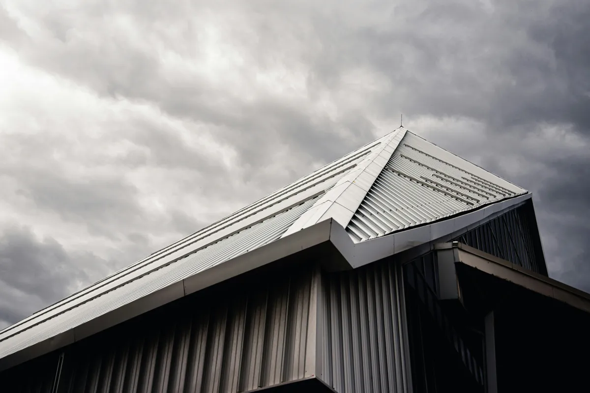 Grey and white house with a ribbed metal roof under cloud