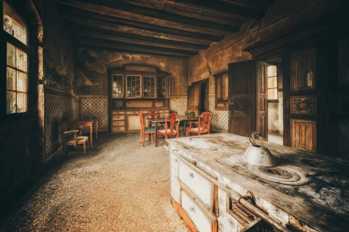 Rustic kitchen with an old stove and wooden chairs