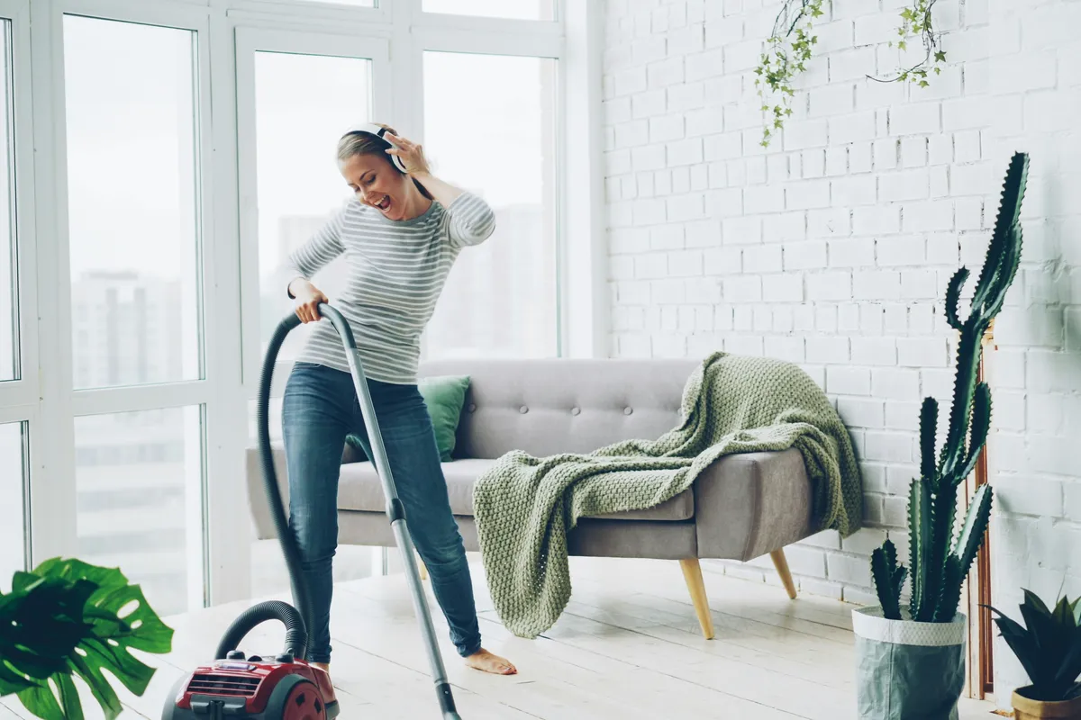Person vacuuming a bright modern living room floor