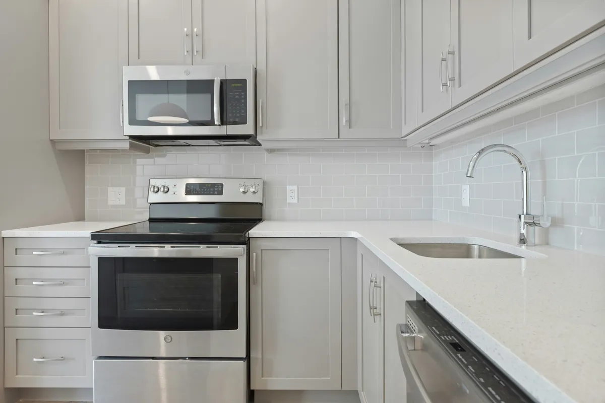 White microwave oven fitted under a wooden kitchen cabinet
