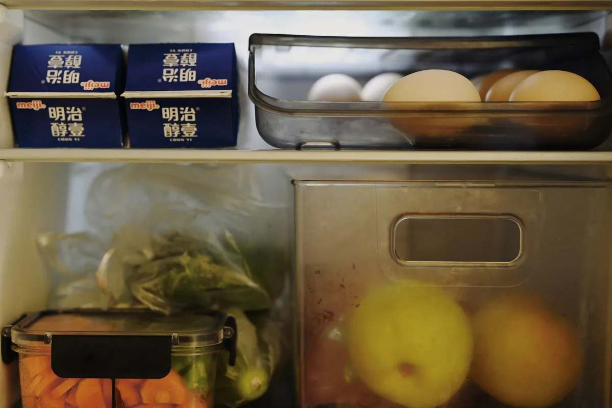 Open refrigerator packed with containers and packets of food