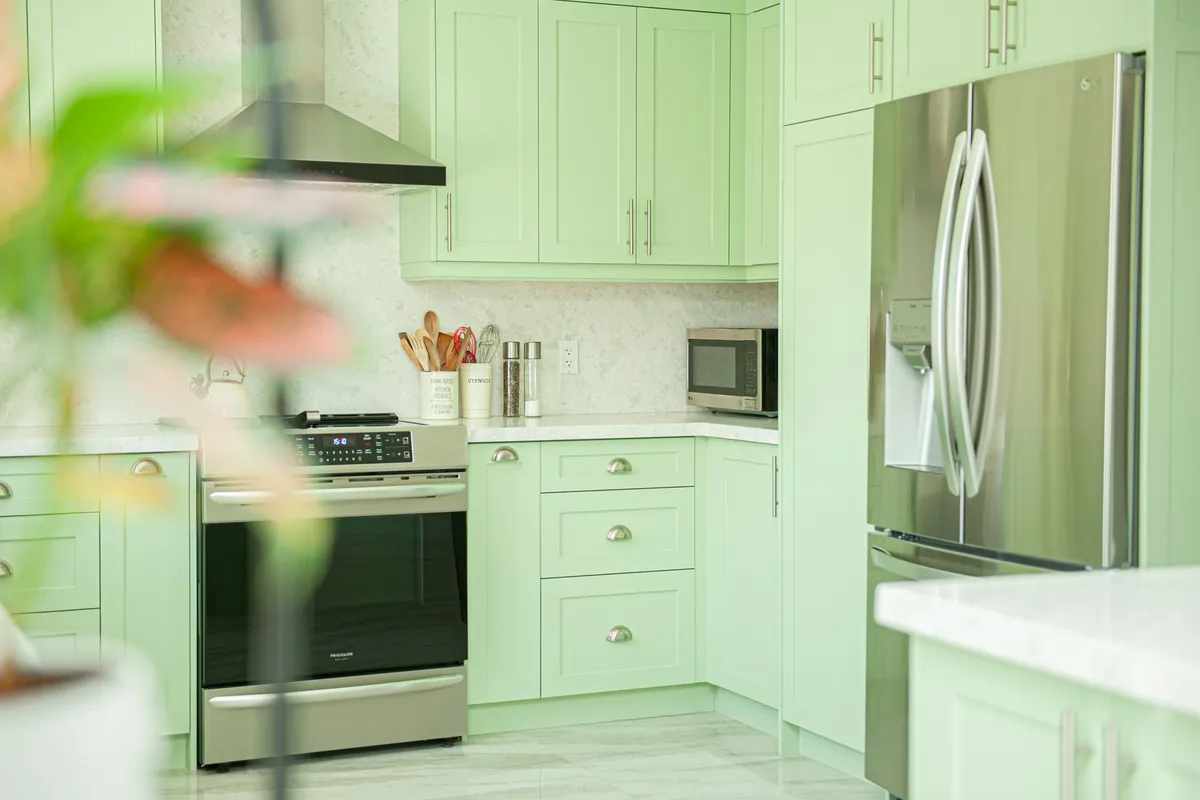 Kitchen with light green cabinets and stainless steel appliances