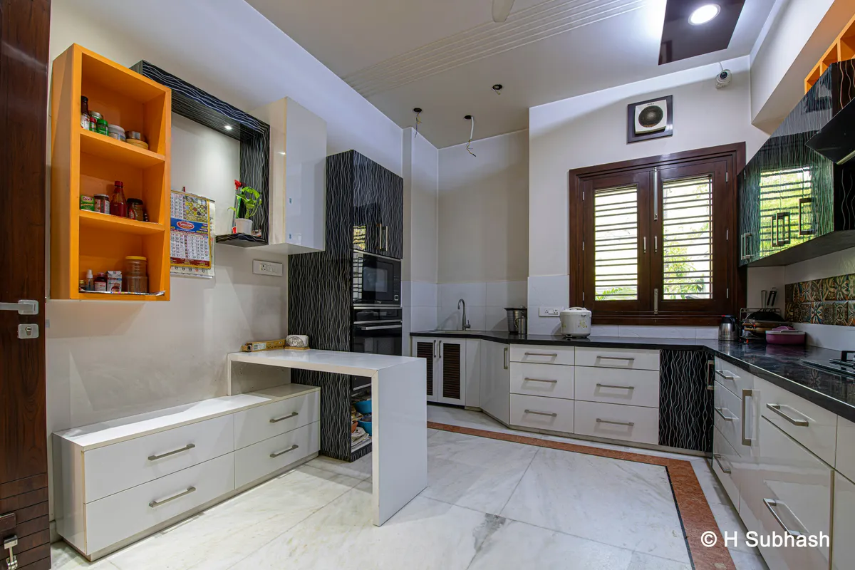 Kitchen with white cabinets, orange shelves and an appliance wall
