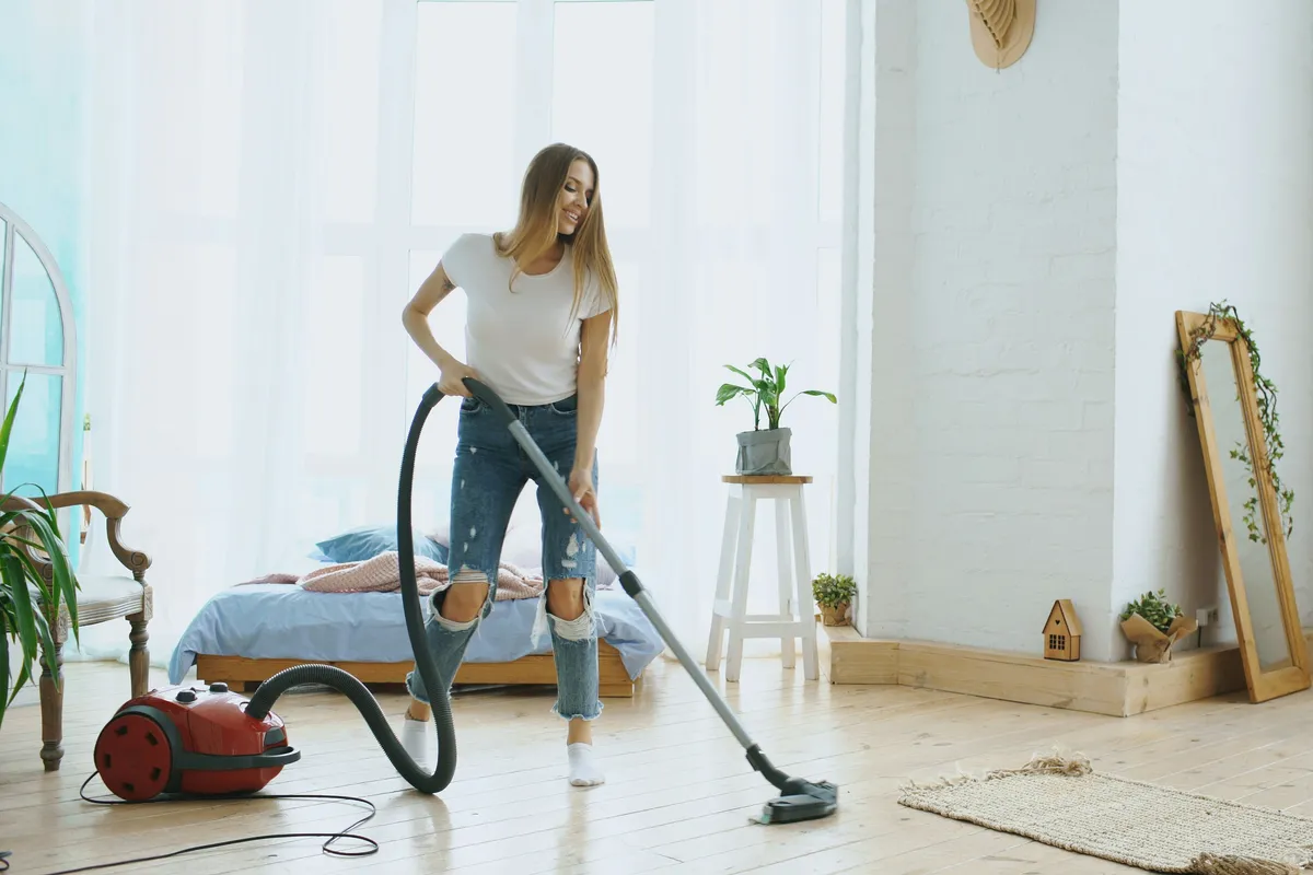 Person vacuuming across a bright modern living room