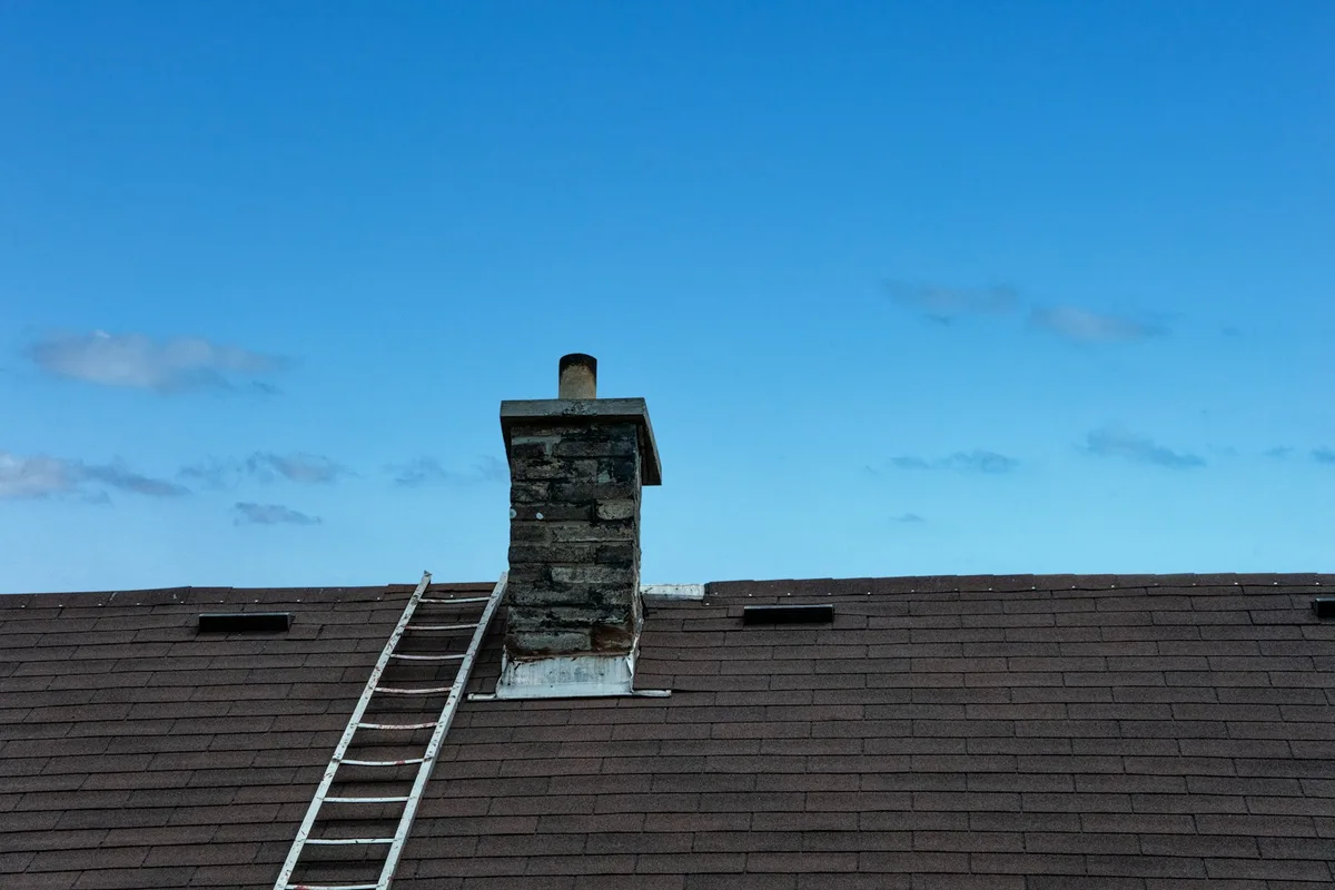 A ladder leaning against the roof of a house during exterior maintenance work