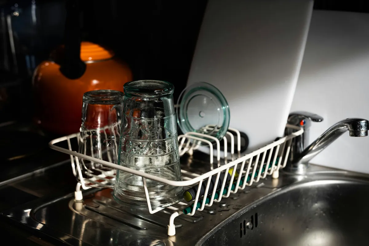 Clear glass mugs upturned on a white metal rack