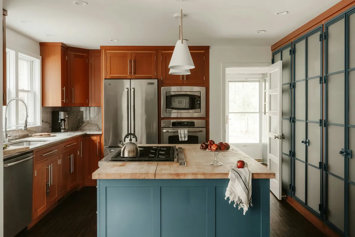 Kitchen with a blue island and wood cabinets on both runs