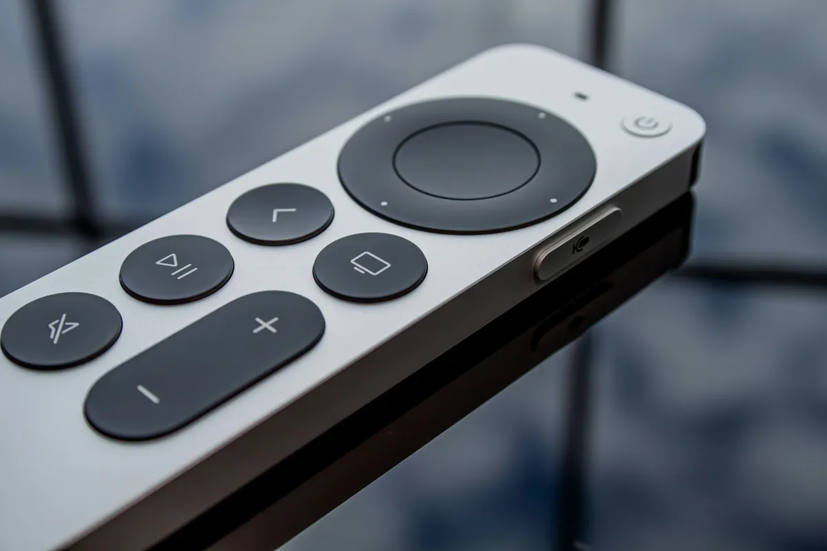 White and black remote control lying on a dark surface