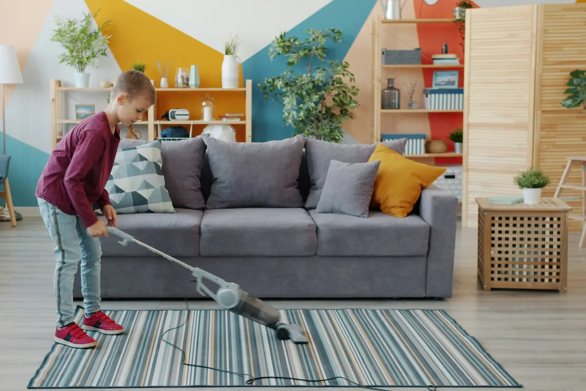 Child vacuuming a striped rug in a living room